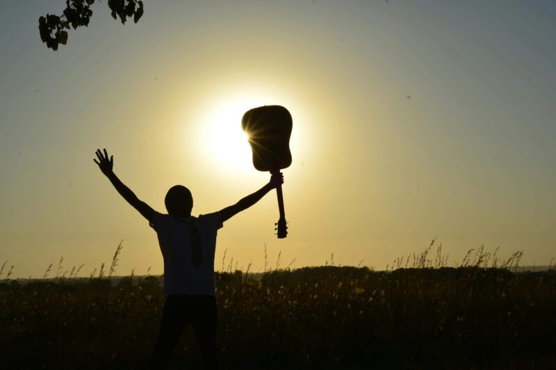 Bible verses about music (man holding a guitar up in praise to Jesus)